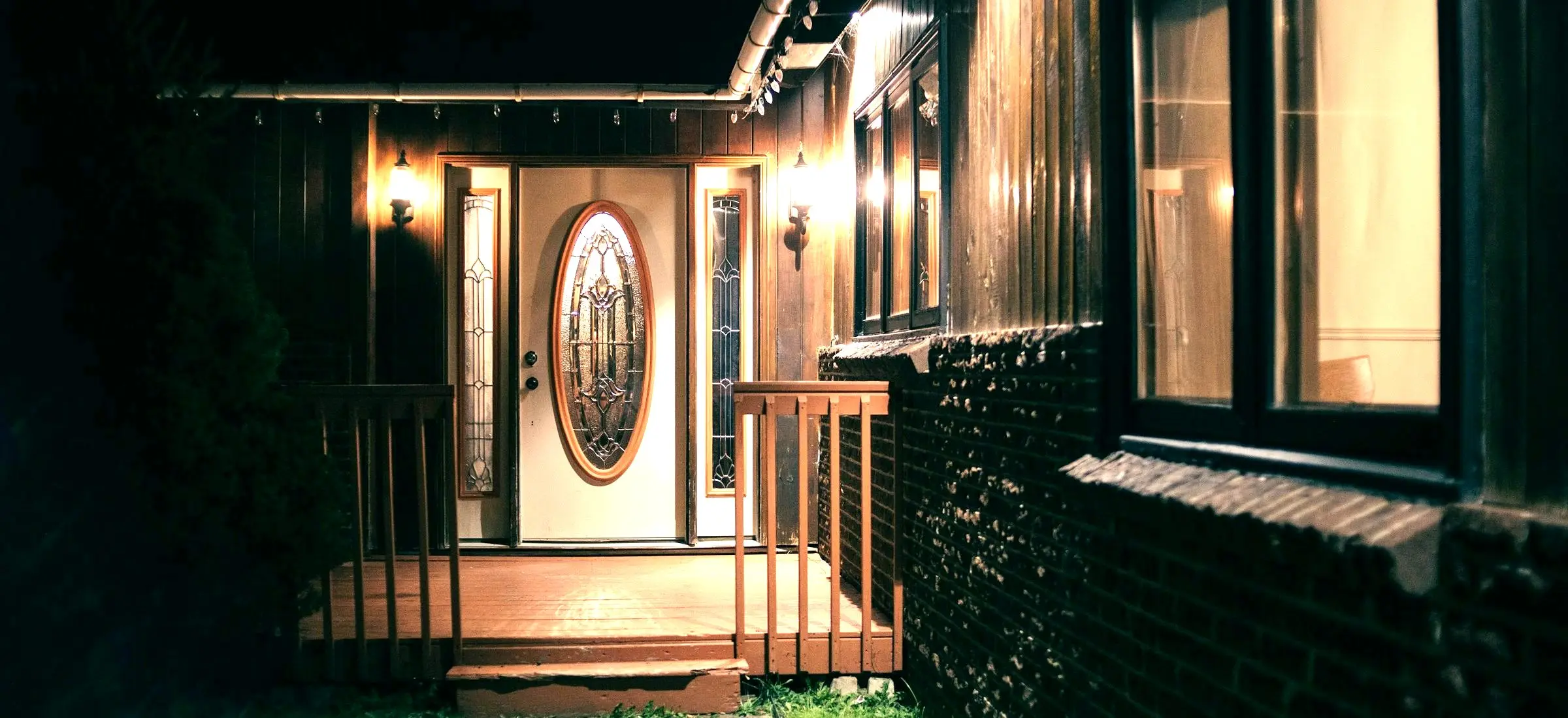 A lit front door on a porch at dusk.